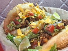 a taco filled with lettuce, tomatoes and other toppings on top of it