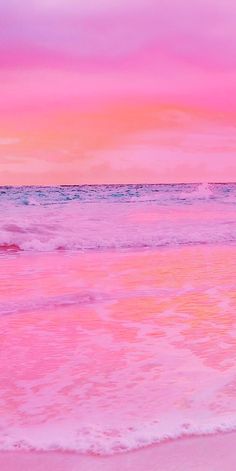 a pink and purple sky over the ocean with waves coming in to shore at sunset