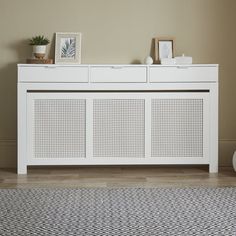 a white sideboard sitting on top of a hard wood floor next to a wall