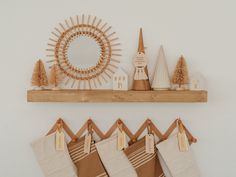 christmas stockings hanging on a wooden shelf in front of a sun mirror and other decorations