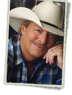 a man wearing a white cowboy hat with his hand on his chin and looking at the camera