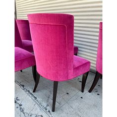 three pink chairs sitting next to each other in front of a garage door on the sidewalk