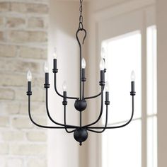 a black chandelier hanging from a brick wall in a room with white walls