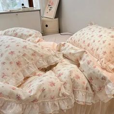 an unmade bed with pink flowers and ruffles