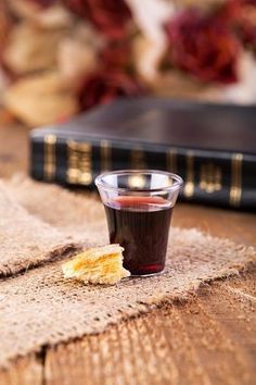 a small glass cup filled with liquid sitting on top of a table next to a book