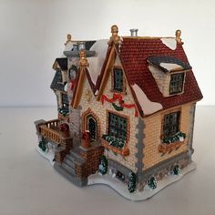 a toy house with snow on the roof and windows, decorated in gold trimmings