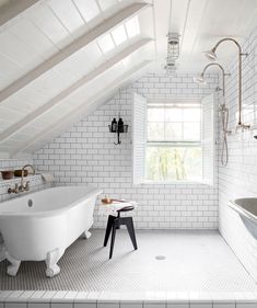 an attic bathroom with white brick walls and flooring, a claw foot bathtub in the center