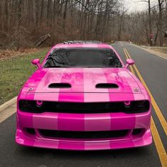 a pink car is parked on the side of the road in front of some trees