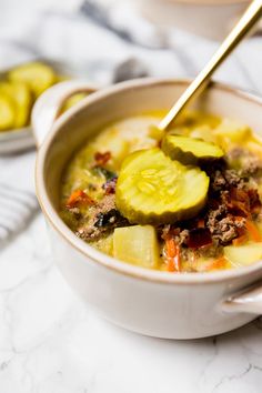 a bowl of soup with cucumbers and meat in it on a marble table