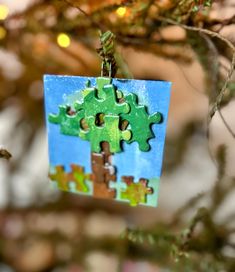 a christmas ornament hanging from a tree with puzzle pieces in the shape of trees