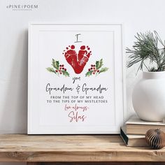 a christmas card with an image of a hand and foot print on it, next to a potted plant