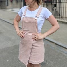 a woman standing on the street with her hands on her hips and wearing an apron