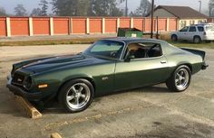 a green muscle car parked in a parking lot