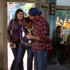 two adults and a child standing in front of an open door with people sitting at tables behind them