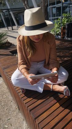 a woman sitting on a wooden bench using a tablet