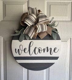 a welcome sign hanging on the front door with a bow in it's center