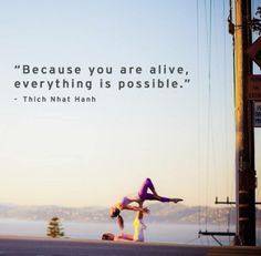 two people doing yoga on the street with a quote above them that says, because you are alive, everything is possible