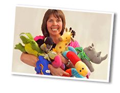 a woman is holding several stuffed animals in her arms, and smiling at the camera