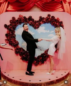 a man and woman standing in front of a heart shaped photo