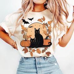 a woman wearing a t - shirt with a black cat and pumpkins on it