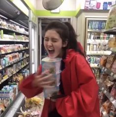 a woman in a red jacket is holding a bag and looking at the food she's selling