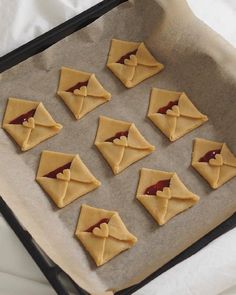 nine cookies with peanut butter and jam in the shape of envelopes on a baking sheet