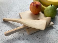 an apple, pears and bananas are sitting on a cutting board next to each other