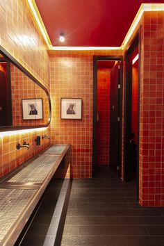 a bathroom with red tiled walls and two sinks in the center, along with mirrors