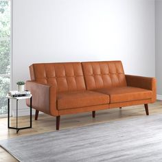 an orange leather couch sitting on top of a wooden floor next to a white wall