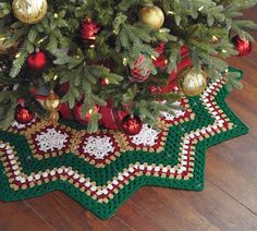 a crocheted christmas tree skirt with ornaments on it