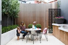 a woman and child sitting at a table in a small patio area with an outdoor grill