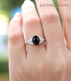 a woman's hand with a black and white diamond ring on top of it