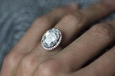 a close up of a person's hand with a diamond ring on their finger