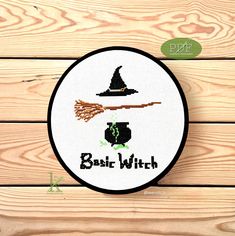 a cross stitch pattern with the words basic witch on it and a witches hat hanging from a broom