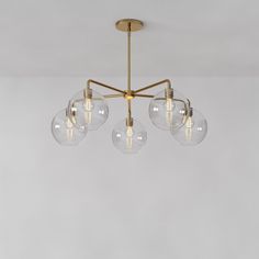 three clear globes hanging from a brass chandelier with four bulbs on each end