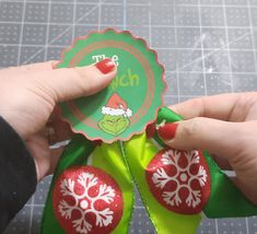 a hand holding a green and red ribbon with white snowflakes on the top