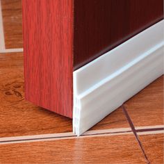 a close up view of the corner of a wooden floor with red and white trim