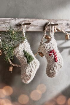 two knitted christmas stockings hanging from a wooden rack with bells and pine cones on them