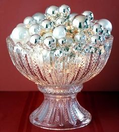 a glass bowl filled with lots of white balls on top of a wooden table next to a red wall