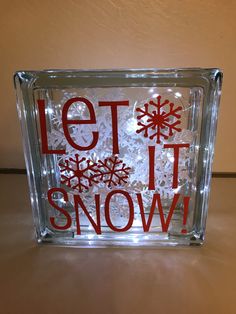 a glass block with snowflakes on it that says let it snow in red