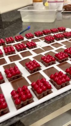 chocolate squares with red frosting are arranged on a checkerboard board in the shape of letters