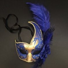 The swan-inspired blue/gold mask for women has arching feathers. Blue Masks And Prosthetics For Carnival Costume Party, Blue Costume Accessories For Carnival Party, Blue Costume Accessories For Carnival, Blue Masks For Carnival Costume Party, Blue Carnival Costume Accessories, Blue Masquerade Mask For Mardi Gras Costume Party, Masquerade Ball Mask Blue, Masquerade Ball Masks Blue, Blue Venetian Masquerade Mask For Party