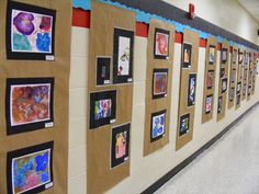 a hallway with many pictures on the wall and one person walking down the hall in front of them