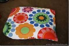 a colorful flowered square pillow on the floor