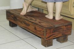 two people standing on top of a wooden bench in front of a kitchen countertop