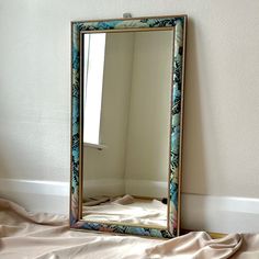 a mirror sitting on top of a bed next to a wall