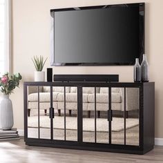 a large flat screen tv mounted on top of a wooden entertainment center in a living room