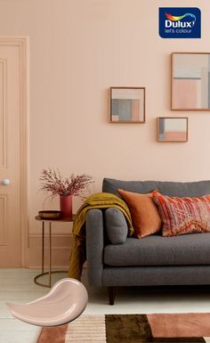 a grey couch sitting in a living room next to a wall with pictures on it