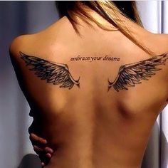 the back of a woman's neck with an angel wing tattoo on her left side