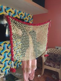 a woman standing in front of a colorful wall hanging from the side of a room